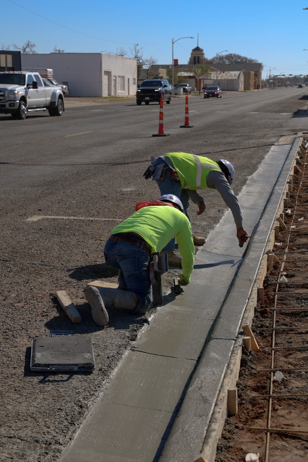Crew screeding concrete curb and gutter work on a commercial site